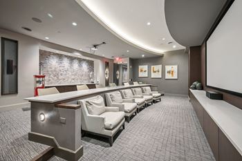A modern home theater with a curved screen and comfortable seating at Everra Midtown Park Apartments, Dallas, TX, 75231